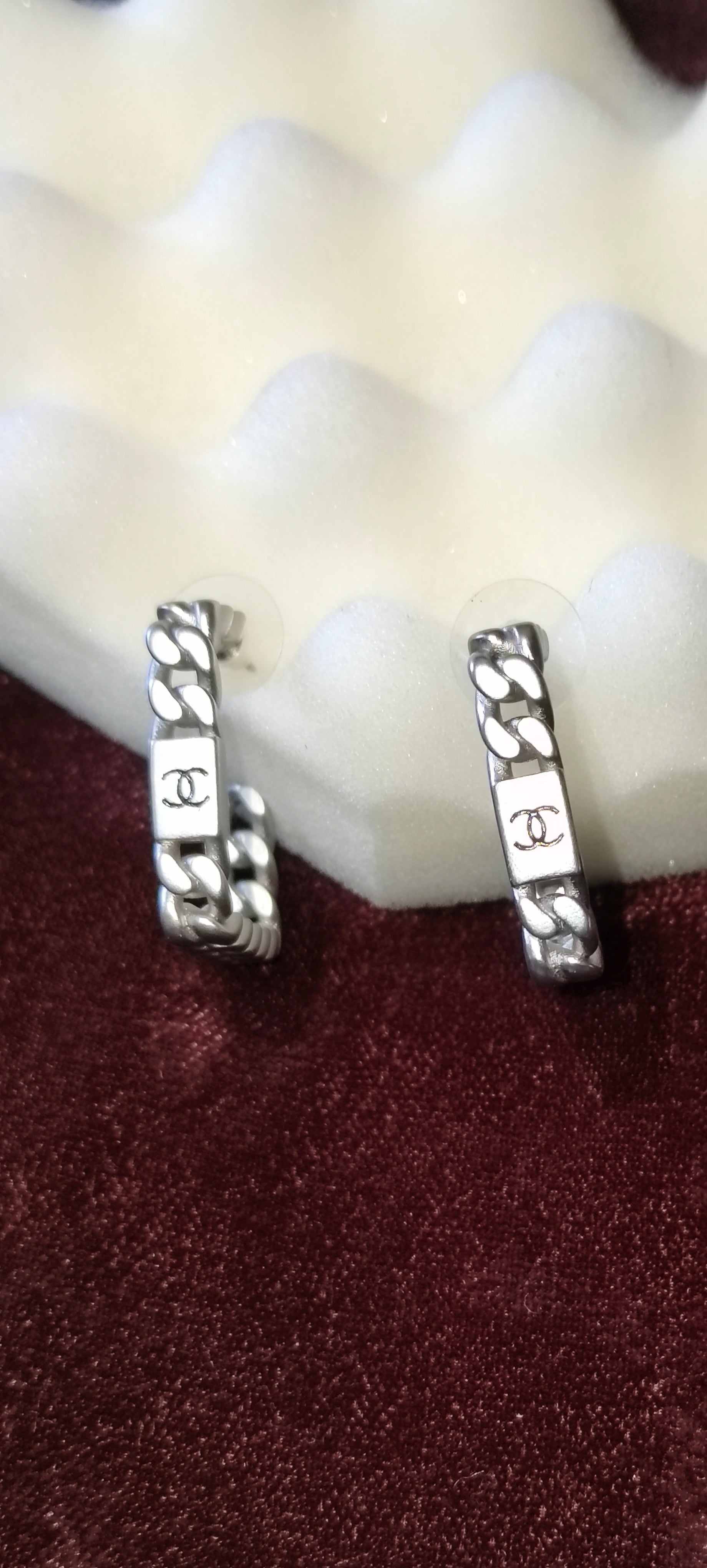 Pair of silver hoop earrings on a textured surface